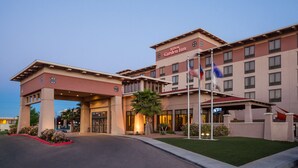 Un Hilton Garden Inn con una estructura de dos pisos, una entrada cubierta y un asta de banderas.