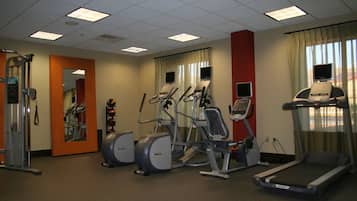 Un gimnasio con cintas de correr, elípticas y máquinas de pesas.