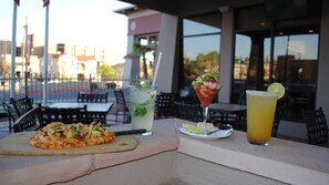 A dining table with a pizza, a cocktail, and a margarita. - Hilton Garden Inn El Paso / University (El Paso)