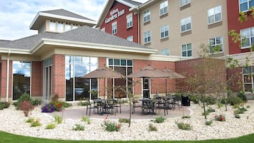 Un hôtel Hilton Garden Inn doté d’un patio avec espace extérieur aménagé, comprenant des sièges et un jardin paysager.