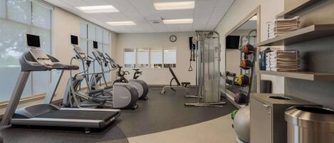 Un gimnasio con cintas de correr, elípticas y equipo de levantamiento de pesas.