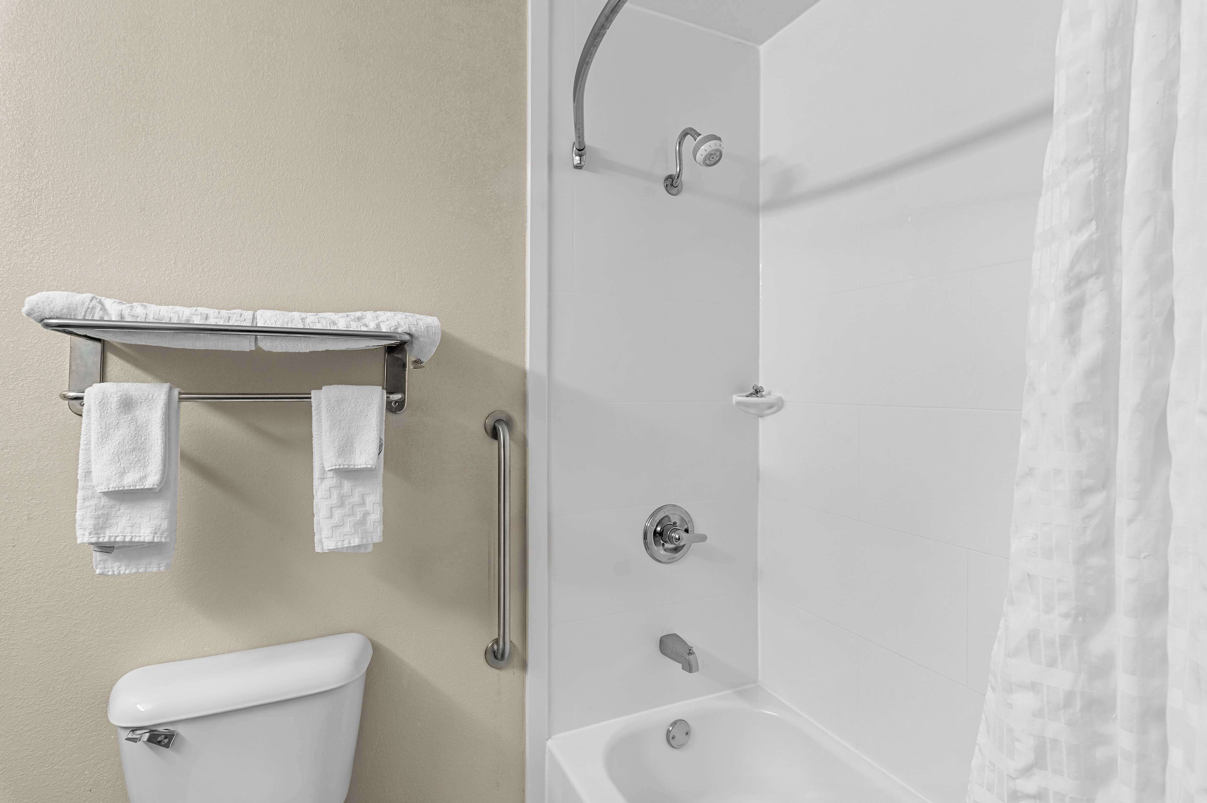 Un baño con inodoro, ducha con puerta de cristal y un perchero con dos toallas.