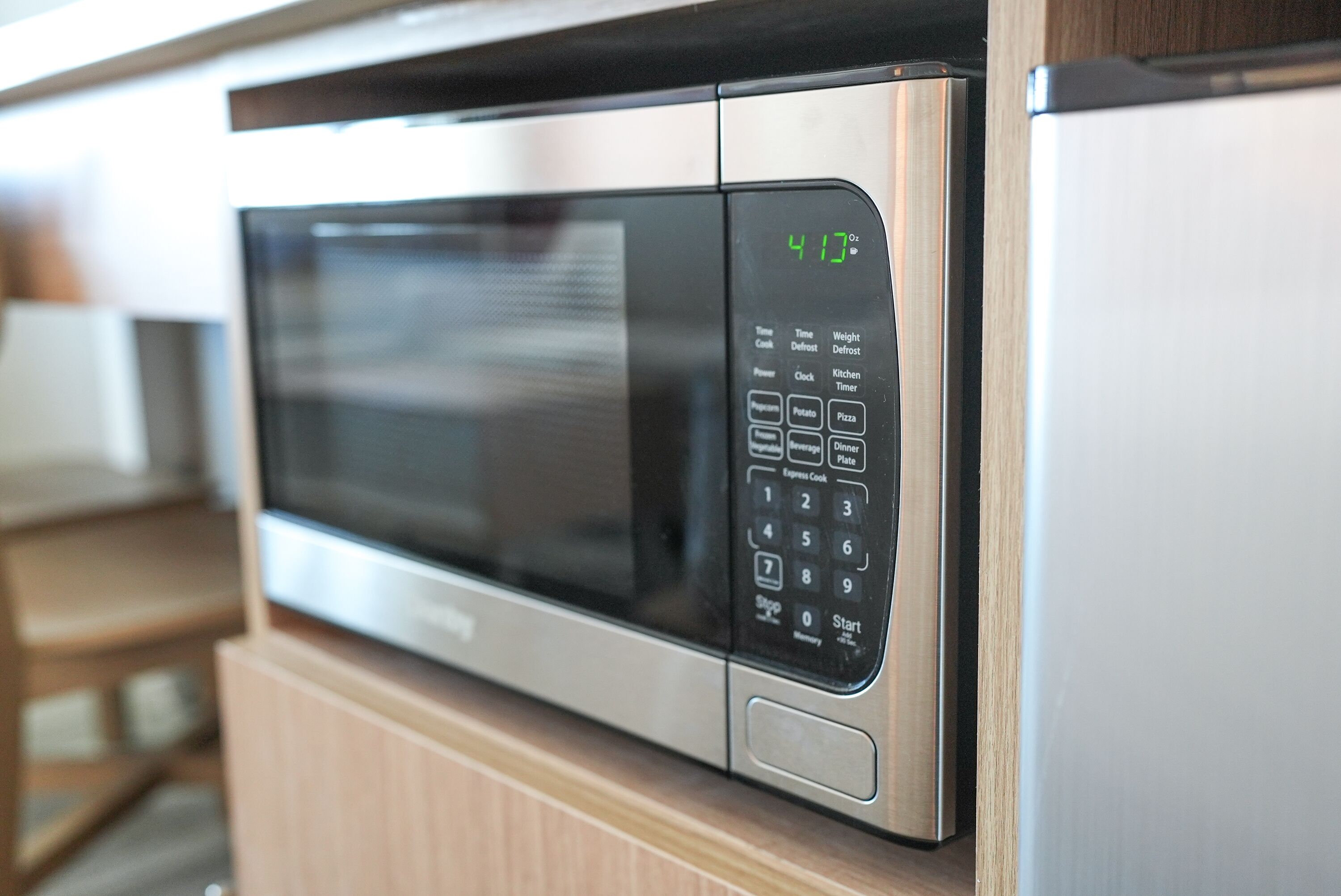 A microwave with a digital display, control panel, and buttons for various functions.