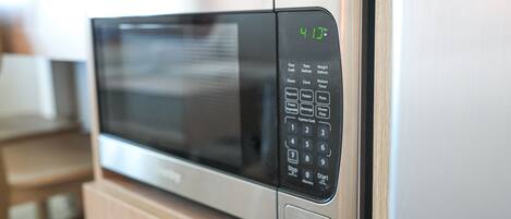 A microwave with a digital display, control panel, and buttons for various functions.