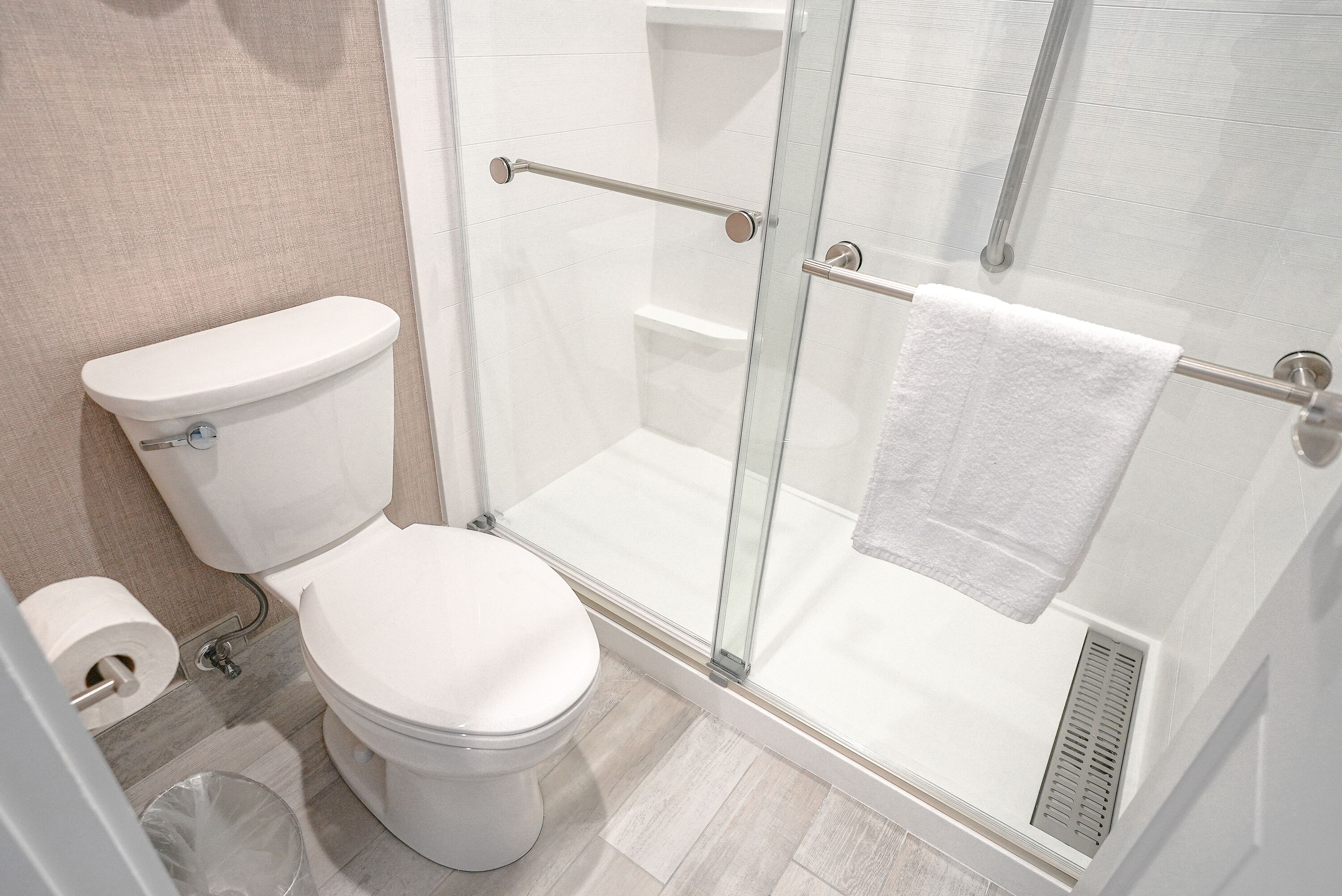 A modern bathroom with a toilet, a glass-enclosed shower, and a towel rack.