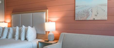 A hotel room with a bed, a nightstand, a lamp, a couch, and a painting on the wall.