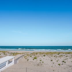 Relax in a serene beachside setting with a clear ocean view, surrounded by a pergola and comfortable seating.