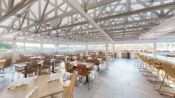 A spacious outdoor dining area with high ceilings and a view of the landscape.