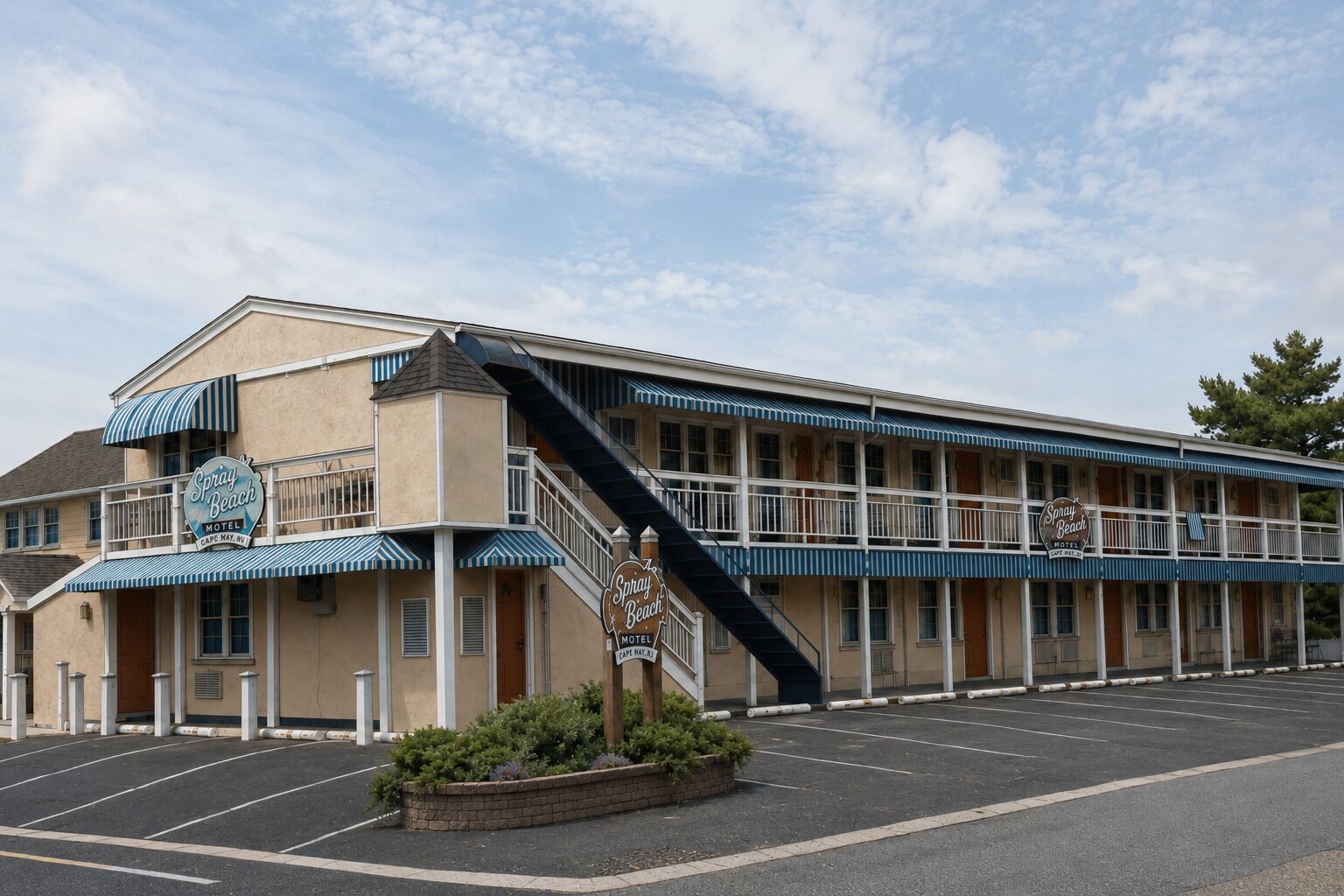 A motel with a two-story structure, a covered parking area, and a staircase leading to the entrance.