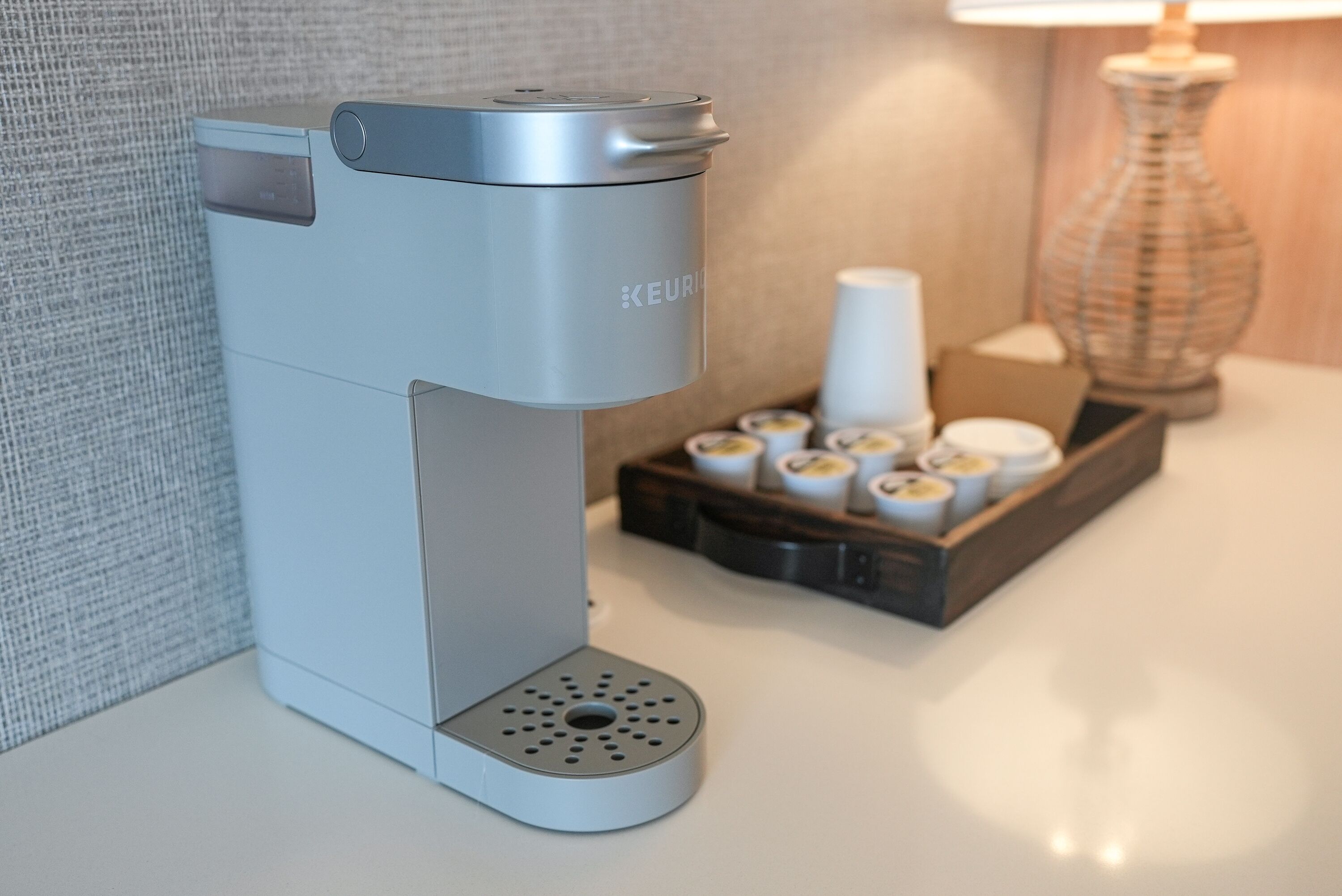 A sleek, modern coffee maker with a compact design, placed on a white countertop.