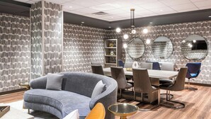 A modern dining area with a grey sofa, wooden dining table, and chairs.