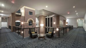 A spacious lobby with a brick wall, two armchairs, a glass table, and multiple exits.
