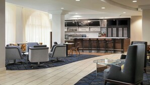 A modern hotel lobby with a bar area, seating arrangements, and a reception desk.