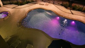A swimming pool with a wavy edge, surrounded by lounge chairs and a tiled deck. - Hampton Inn & Suites Austin Cedar Park-Lakeline (Austin)