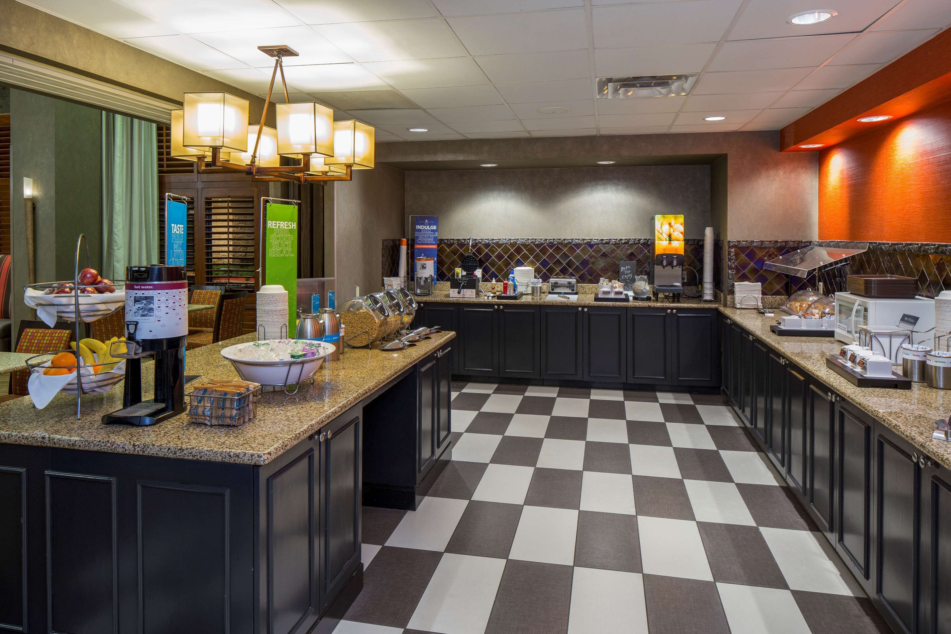 A hotel kitchen with checkered flooring, granite countertops, and modern appliances.