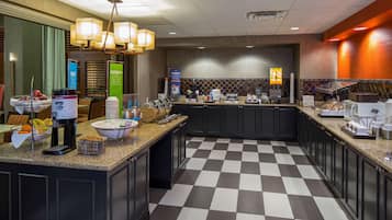 A hotel kitchen with checkered flooring, granite countertops, and modern appliances.