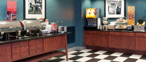 A breakfast bar with a coffee machine, toaster, and food display.