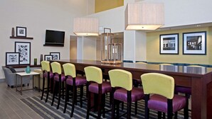 A conference room with a long table, multiple chairs, a television, framed pictures, and pendant lighting. - Hampton Inn & Suites Bloomington - Normal (Normal)