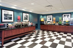 A breakfast bar with a checkered floor, a microwave, and various food items.
