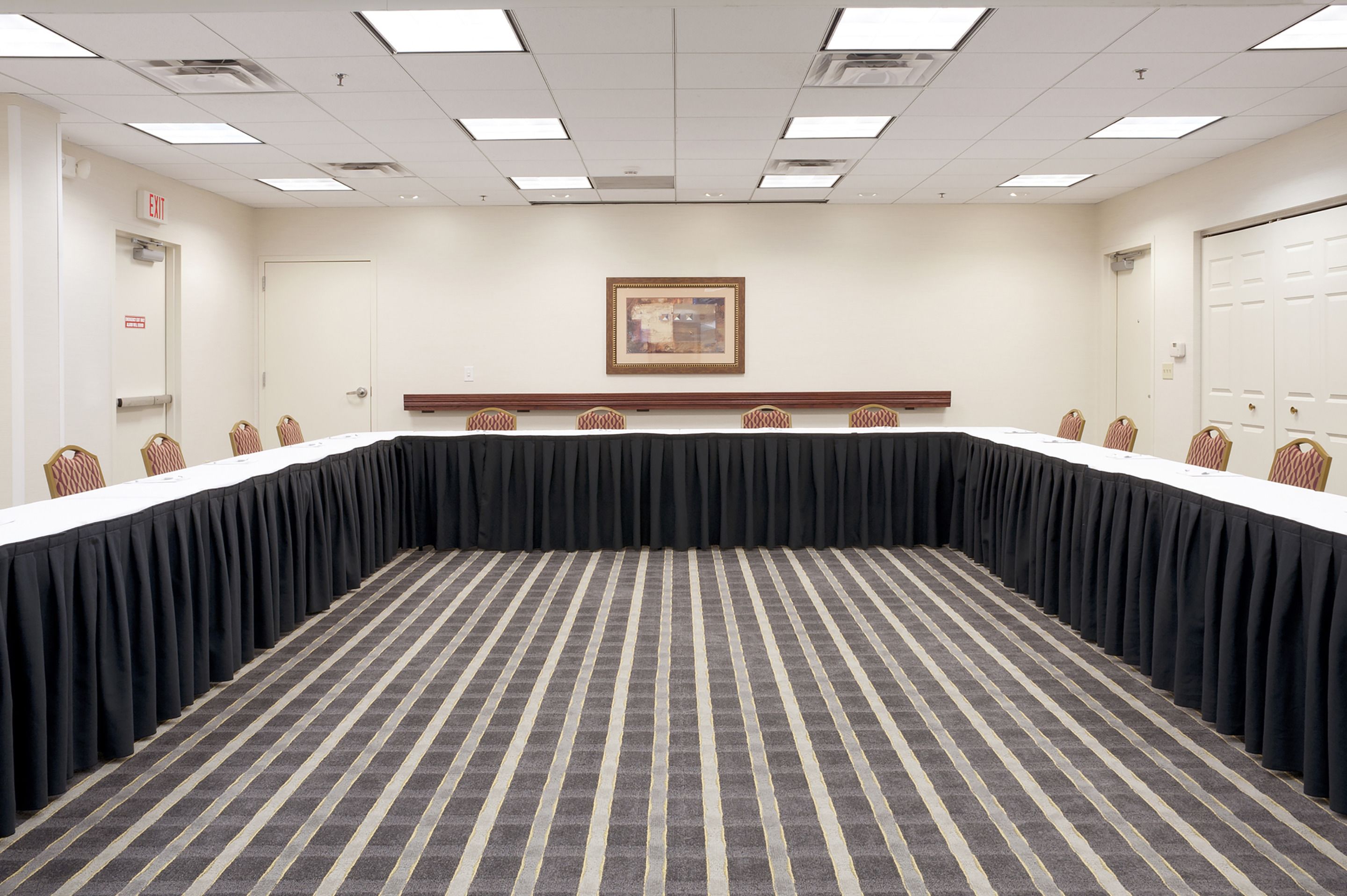A conference room with a long table, chairs, and a carpeted floor.