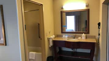 A bathroom with a sink, mirror, and shower.