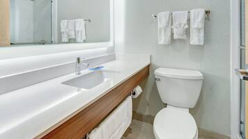 A modern bathroom with a white sink, a mirror, a toilet, and a shower.
