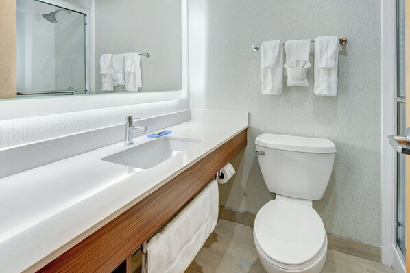A modern bathroom with a white sink, a mirror, a toilet, and a shower.