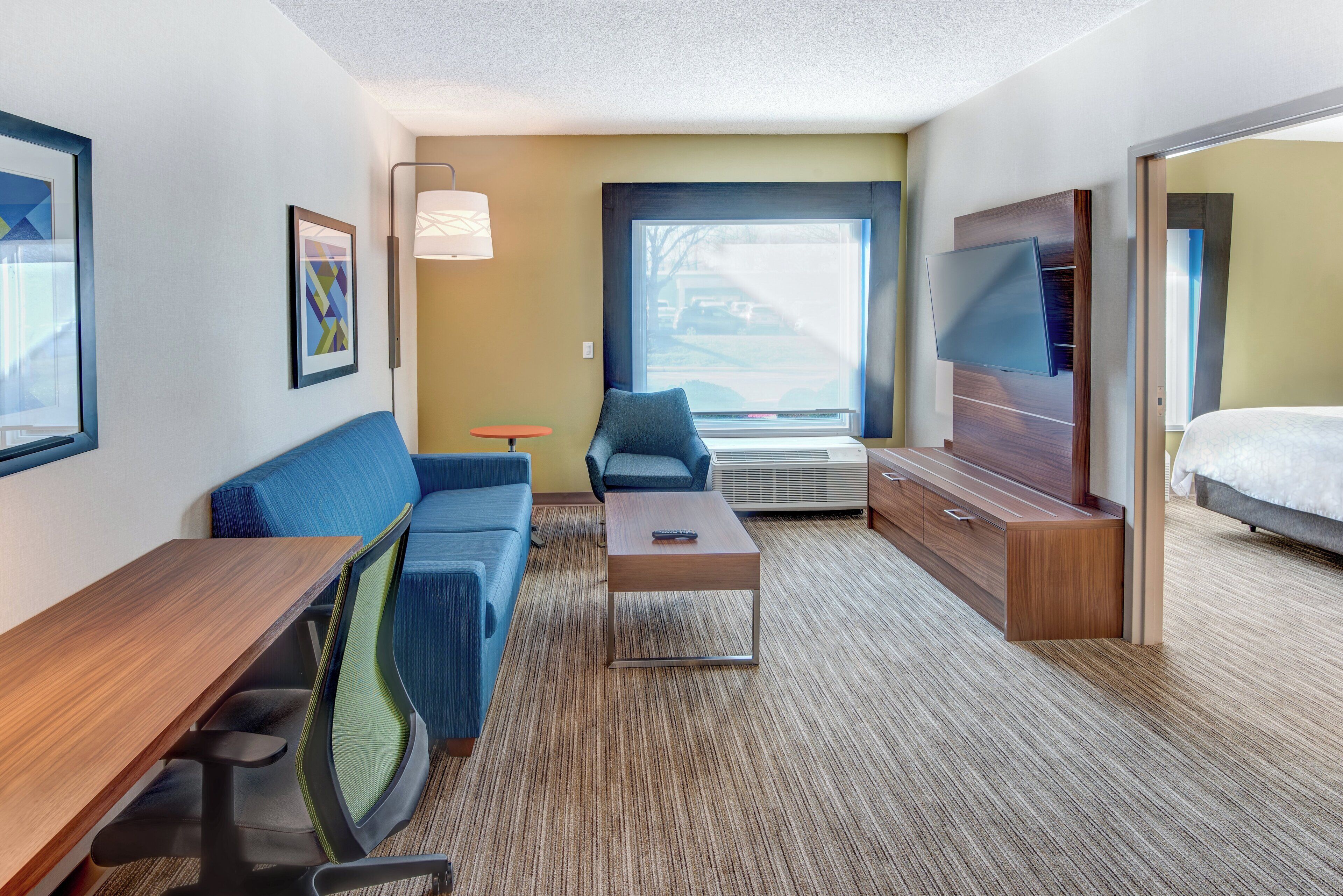 Une chambre d’hôtel avec un canapé, une petite table, un téléviseur et un lit.