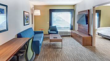 Une chambre d’hôtel avec un canapé, une petite table, un téléviseur et un lit.
