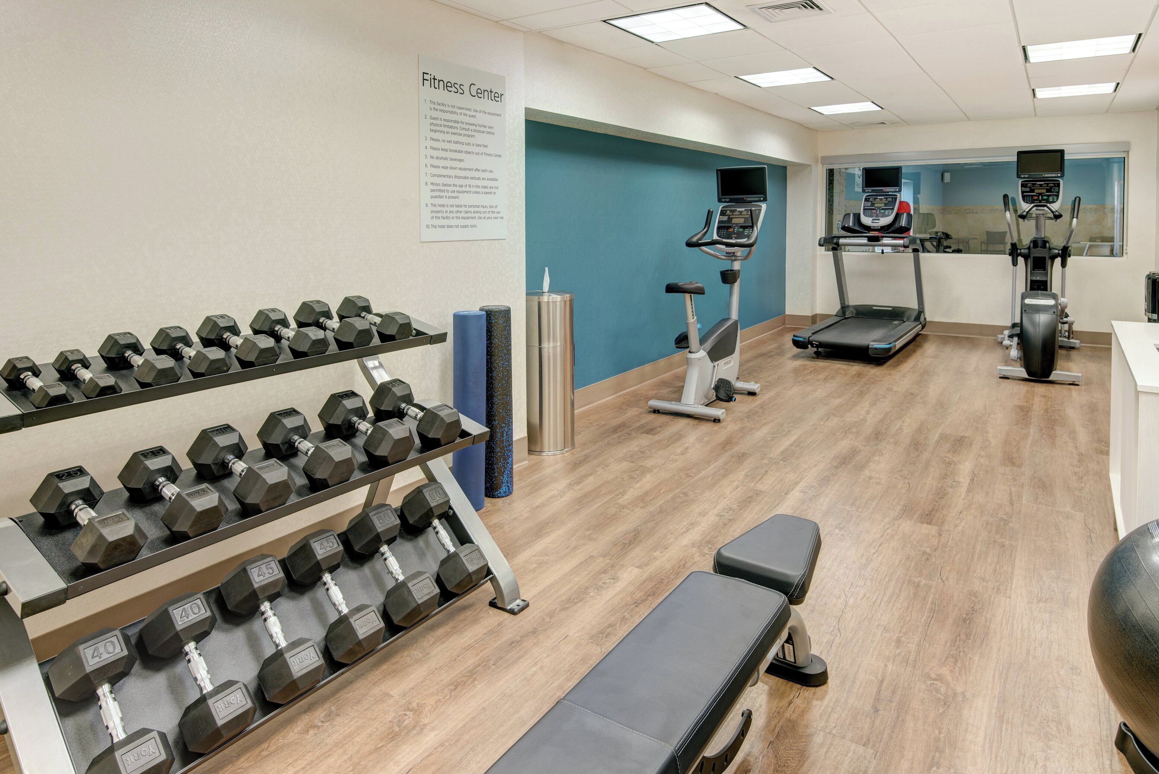 Et fitnesscenter med håndvægte, løbebånd og crosstrainer.