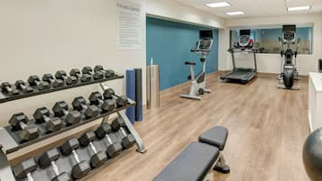 Et fitnesscenter med håndvægte, løbebånd og crosstrainer.