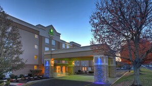 Un hotel Holiday Inn Express con fachada moderna, un acceso cubierto y un estacionamiento.