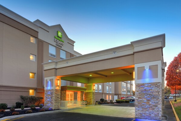 Un hotel Holiday Inn Express con entrada cubierta, fachada de piedra y aparcamiento.