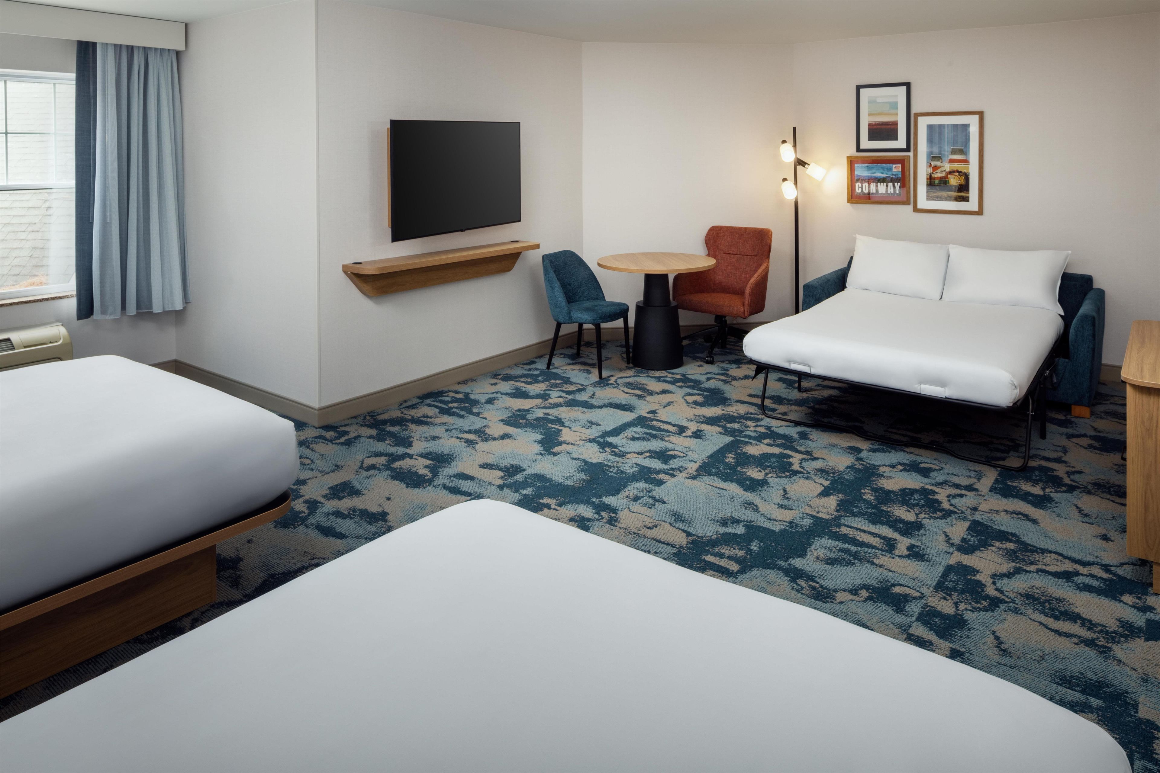 Une chambre d’hôtel avec deux lits, une télévision, une petite table et une chaise.