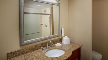 A bathroom with a granite countertop, a sink, a mirror, a towel rack, and a toilet.