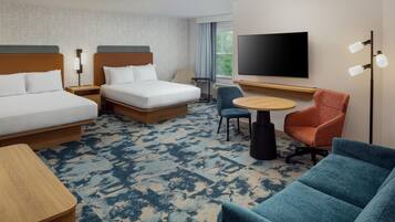 A hotel room with two beds, a TV, a desk, and a chair.