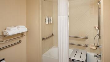 A modern bathroom with a bathtub, shower, and handrails.