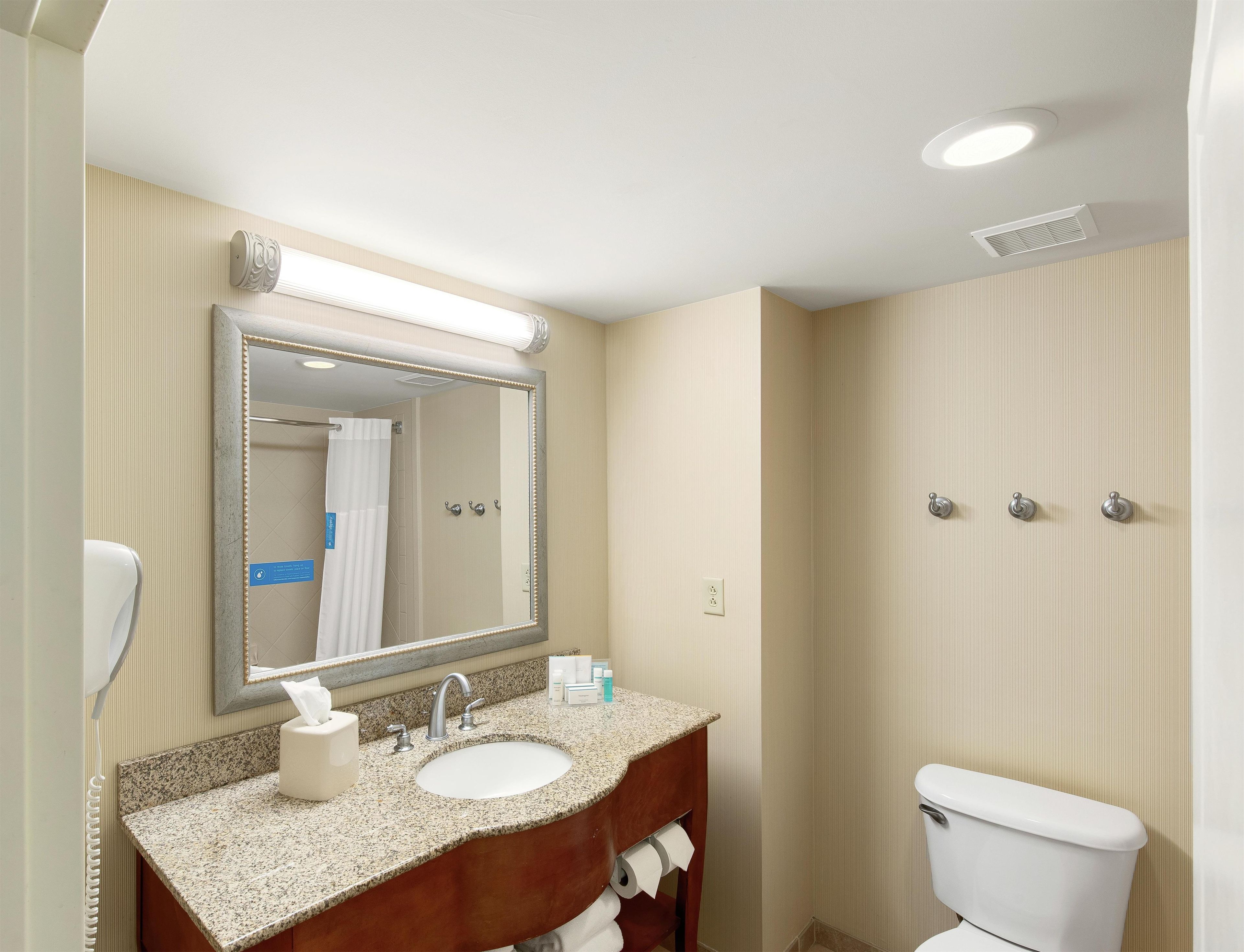 Une salle de bain équipée d’un lavabo, d’un miroir, de toilettes et d’un porte-serviettes.