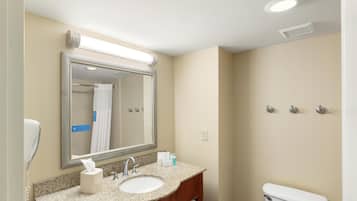 Une salle de bain équipée d’un lavabo, d’un miroir, de toilettes et d’un porte-serviettes.
