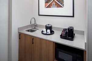 A modern kitchen with a sink, coffee machine, and a framed picture of a building.