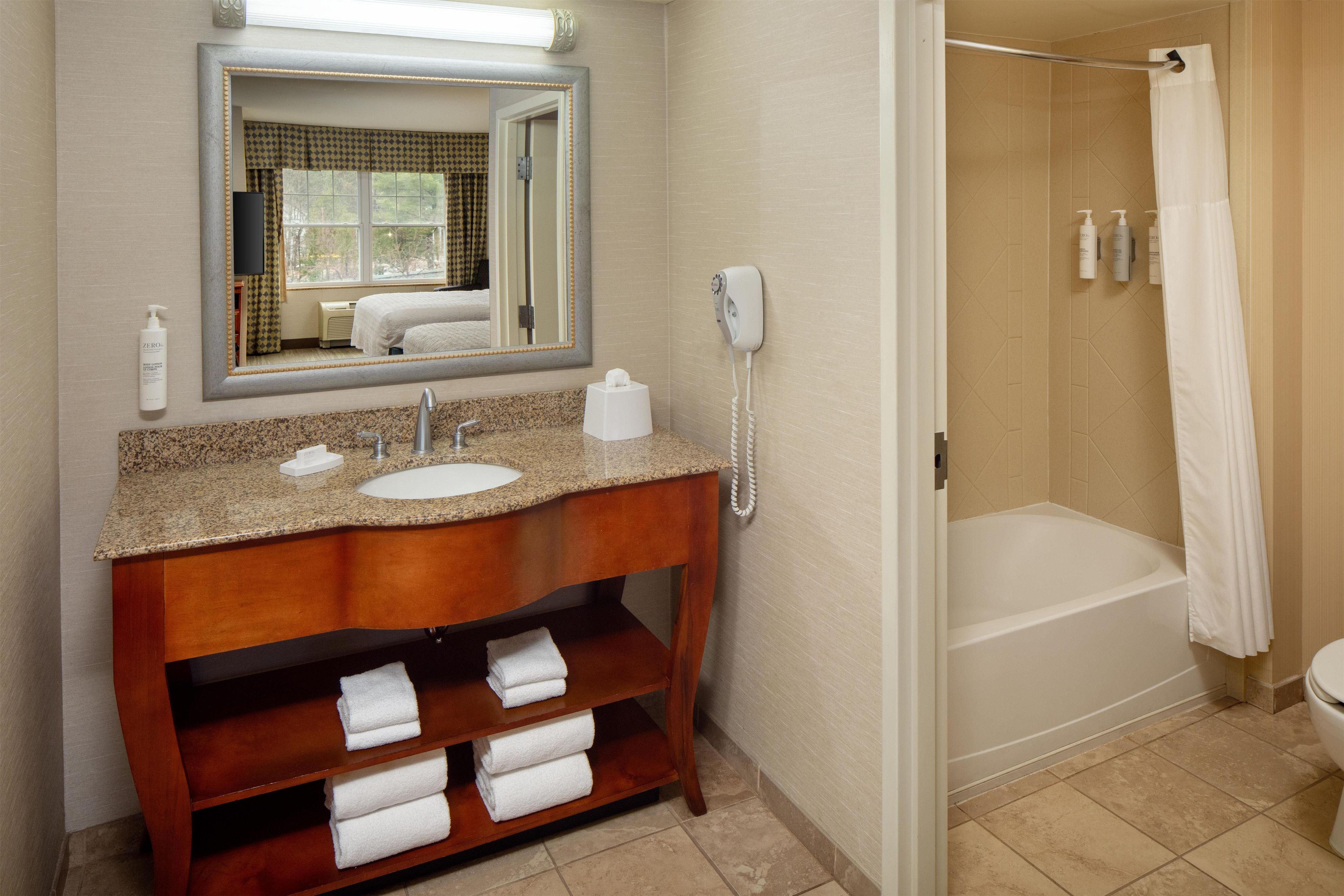 A bathroom with a sink, mirror, towel rack, and a shower area.