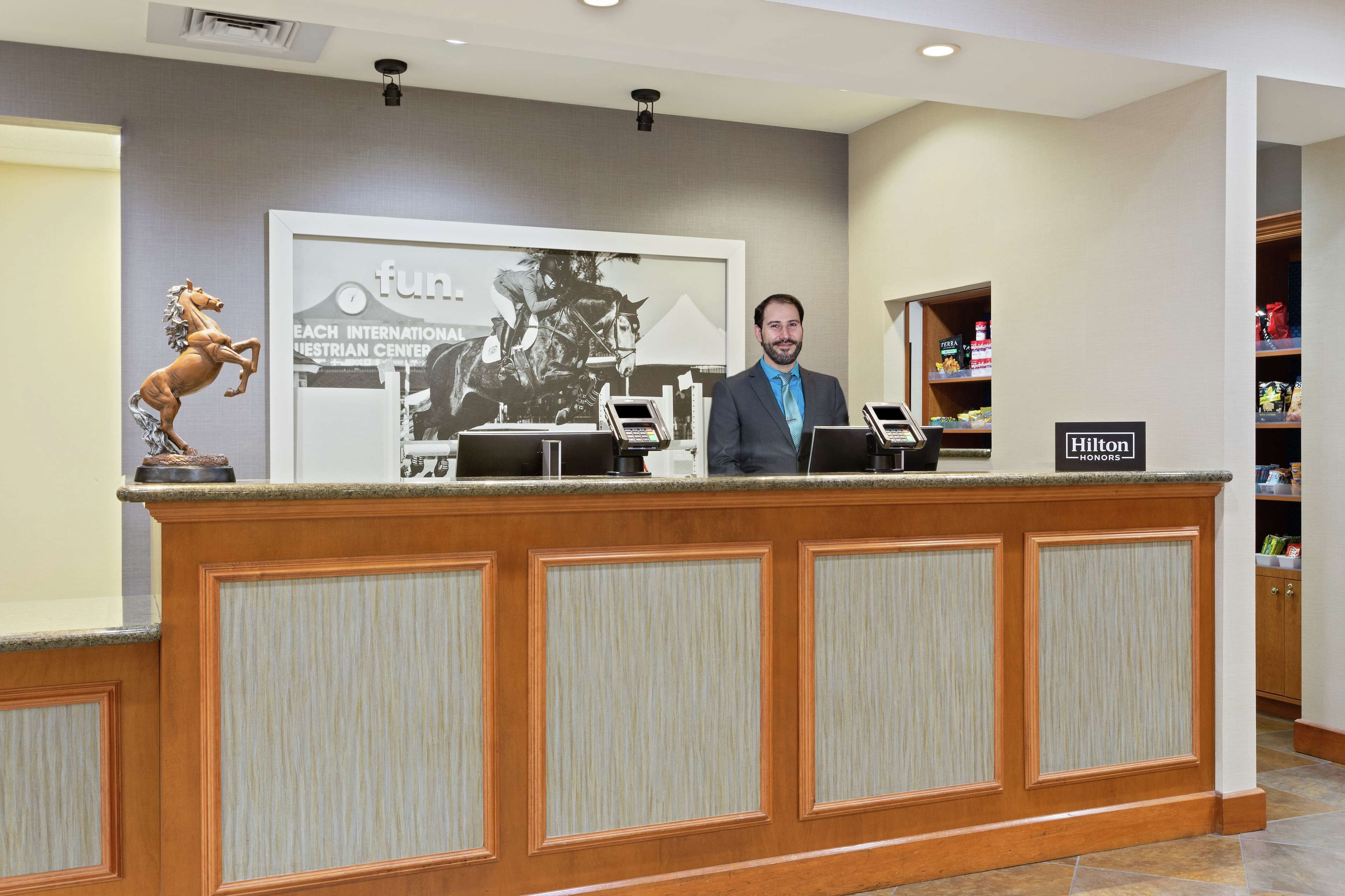 A reception desk with a horse statue, a framed picture of a horse race, and a sign for Hilton Honors.