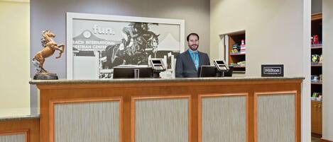 A reception desk with a horse statue, a framed picture of a horse race, and a sign for Hilton Honors.