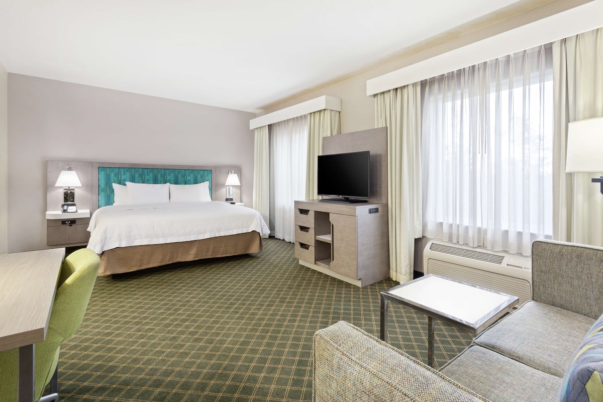 Una habitación de hotel con cama, televisión, escritorio y una silla.