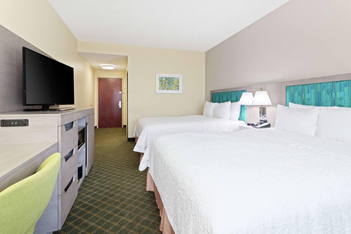 Habitación de hotel con dos camas, televisión, escritorio y silla.