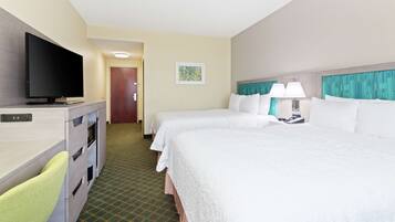 A hotel room with two beds, a TV, a desk, and a chair.