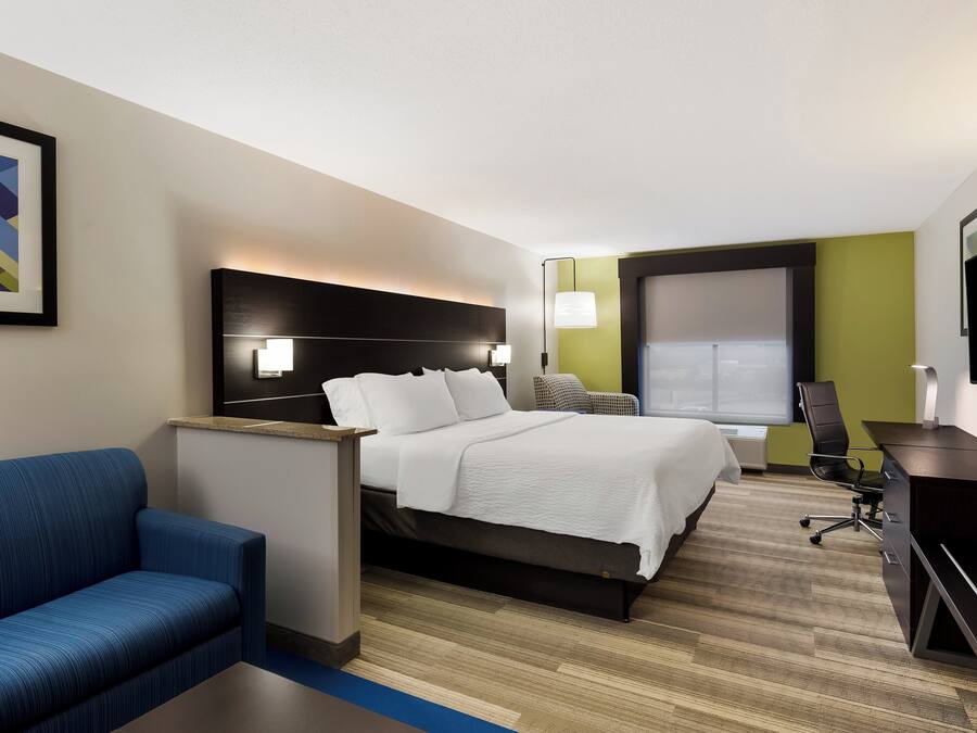 Habitación de hotel con cama, escritorio, silla, sofá y televisor.
