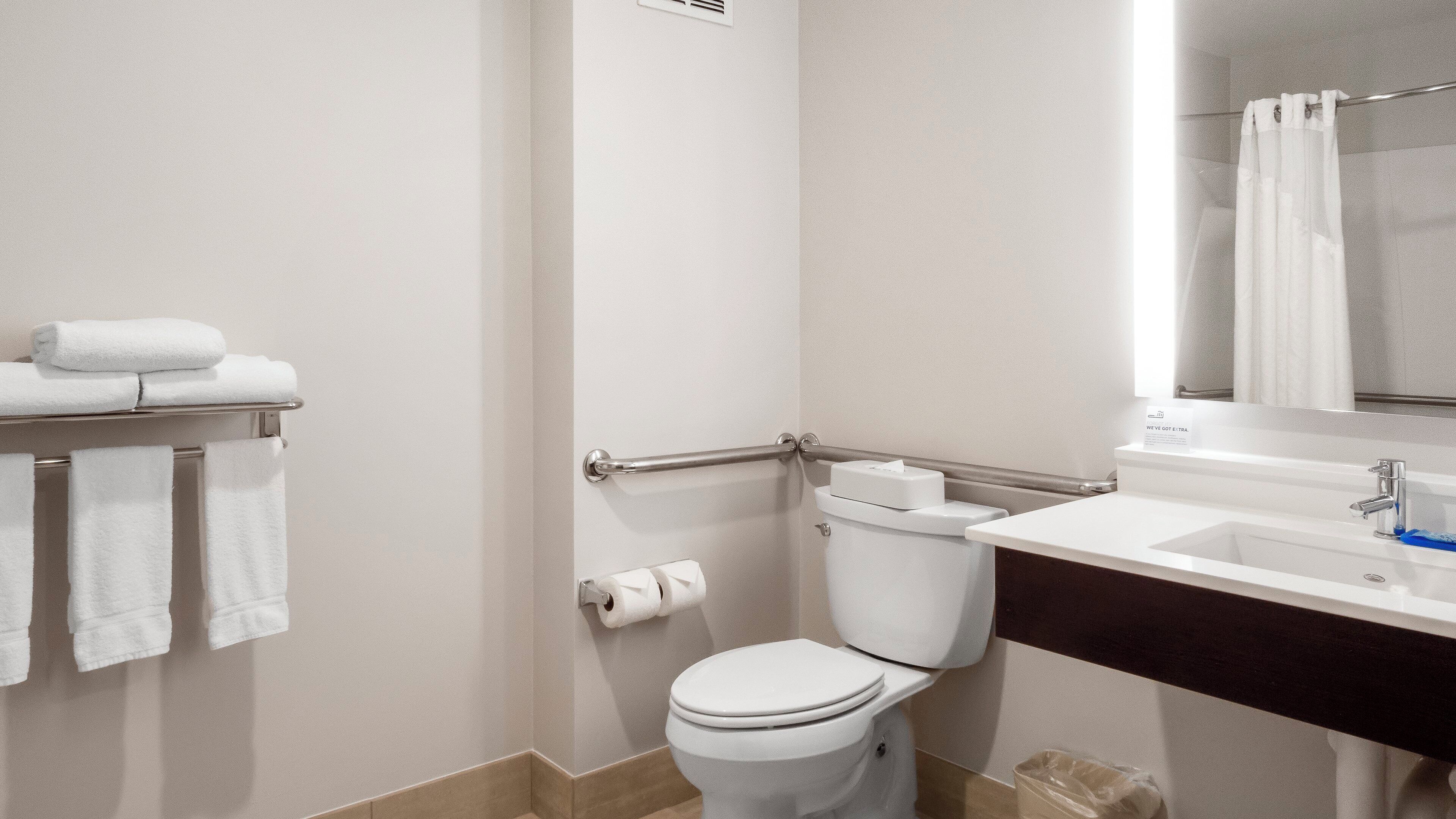 Une salle de bain équipée de toilettes, d’un lavabo, d’un porte-serviettes et d’un rideau de douche.