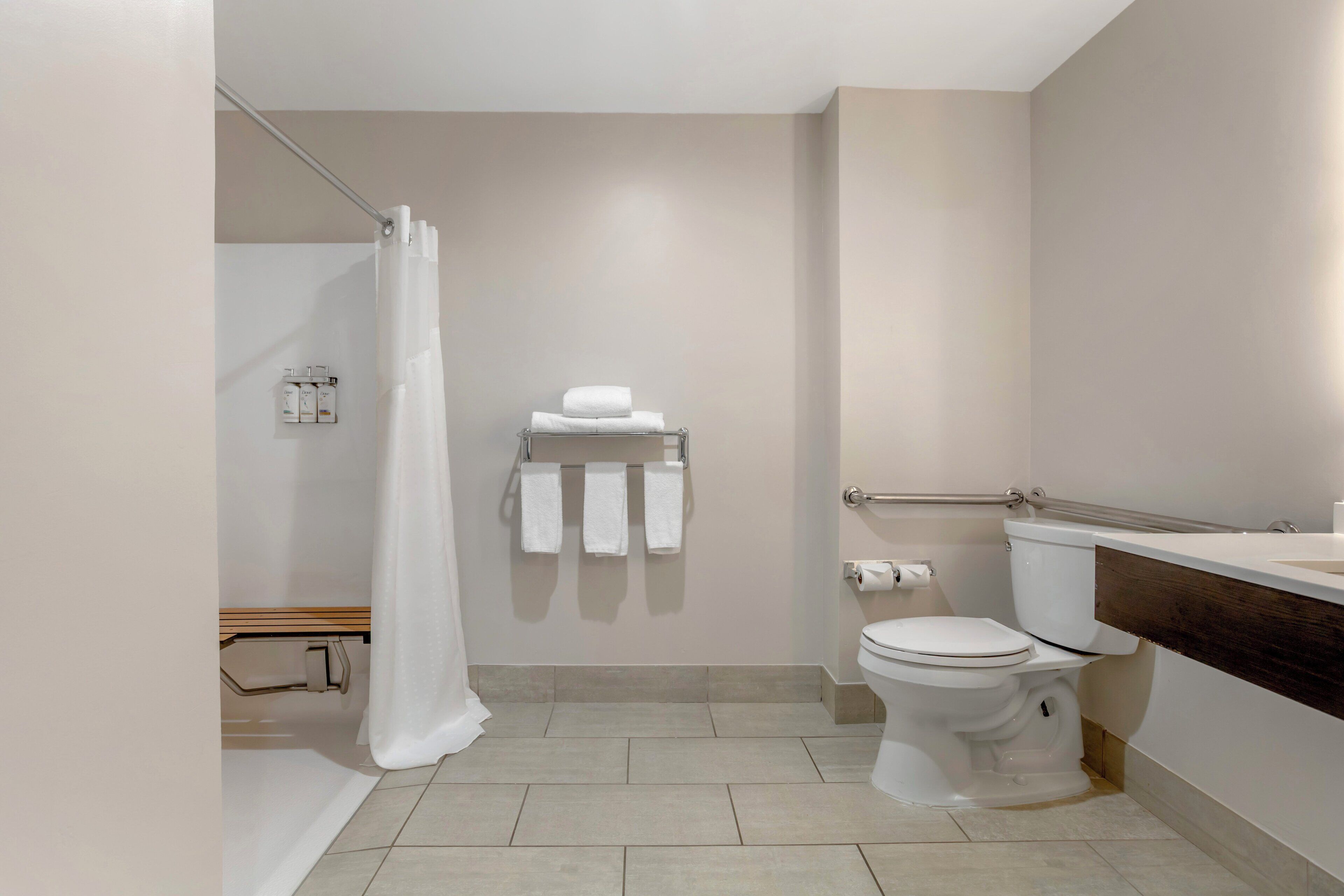 A modern bathroom with a toilet, a shower curtain, and a towel rack.
