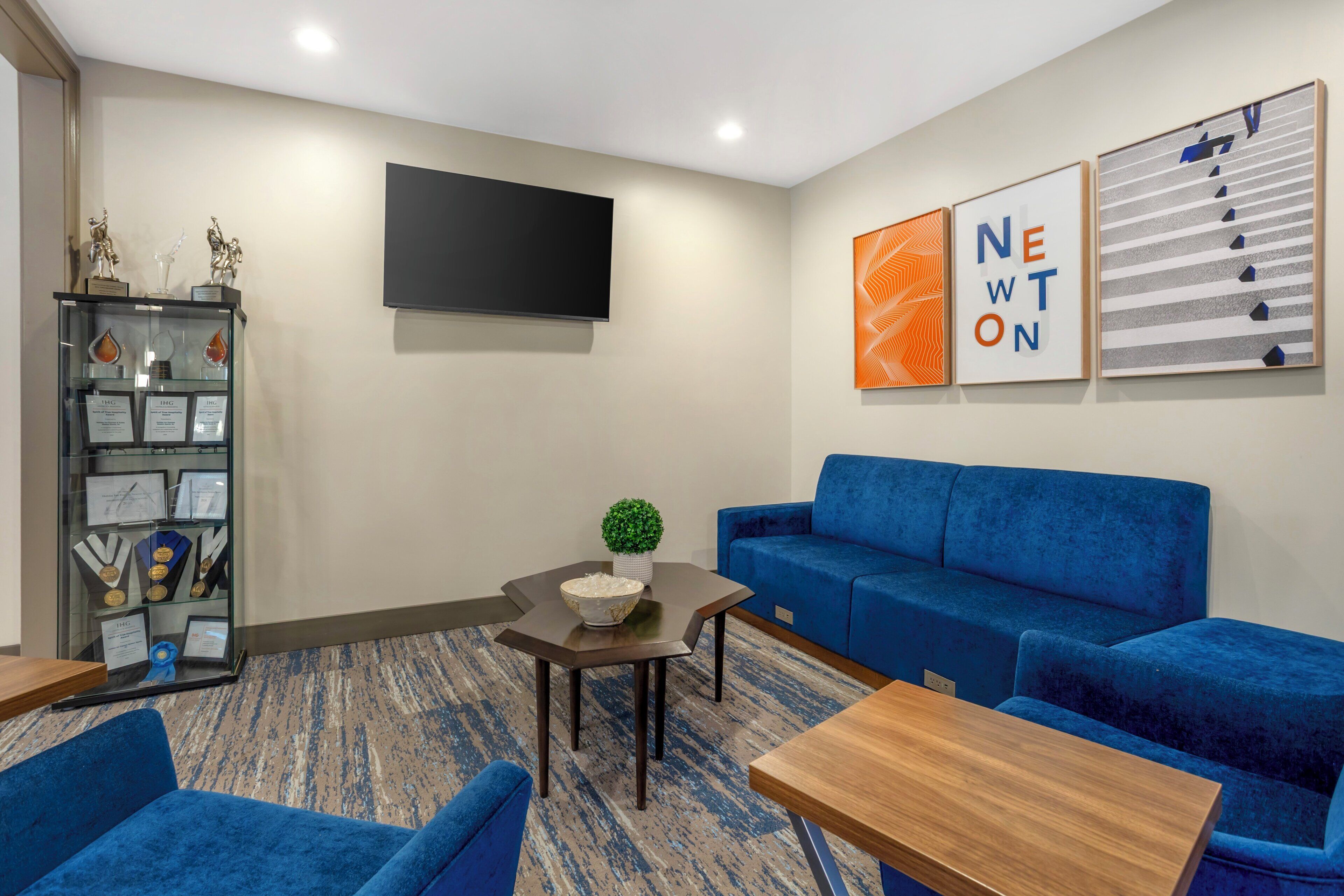 Una sala de estar moderna con un sofá azul, una mesa de centro y un televisor de pantalla plana montado en la pared.